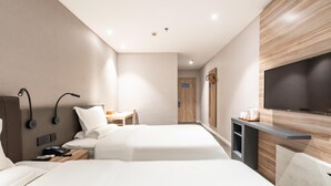 Una habitación de hotel moderna con dos camas, un escritorio, una silla, un televisor y un armario.