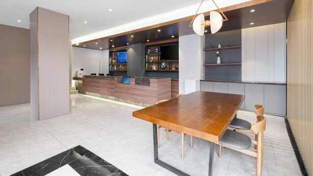 Una cocina moderna con una isla integrada, un comedor con mesa y sillas de madera, y un televisor montado en la pared.