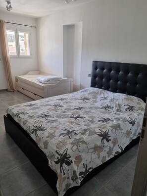 A bedroom with a large bed, a bedside table, and a window with curtains.
