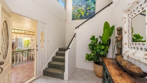 Un escalier avec une rampe, une plante en pot et un miroir décoratif.