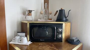 A kitchen counter with a microwave, coffee maker, and coffee cups.