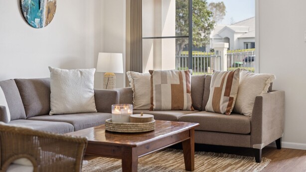 Ein modernes Wohnzimmer mit grauem Sofa, einem Holztisch und einem Korbstuhl.