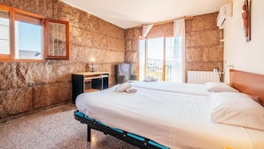 A hotel room with a large bed, a desk, a chair, and a view of the city through the window.