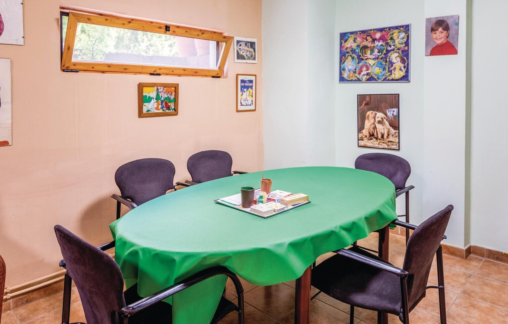 Un salón de conferencias con una mesa verde, seis sillas y varias fotografías enmarcadas en las paredes.