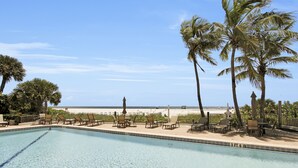 A pool with lounge chairs and palm trees, overlooking a beach. - Beachfront 3/2 Penthouse Lido Key Beautiful Views! (Sarasota)