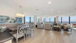 A spacious living room with a dining area, large windows offering city views, and modern decor. - Beachfront 3/2 Penthouse Lido Key Beautiful Views! (Sarasota)