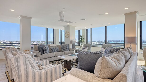 A spacious living room with a high ceiling, large windows offering a city view, and a ceiling fan. - Beachfront 3/2 Penthouse Lido Key Beautiful Views! (Sarasota)