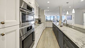 A modern kitchen with stainless steel appliances, white cabinetry, and a marble countertop. - Beachfront 3/2 Penthouse Lido Key Beautiful Views! (Sarasota)