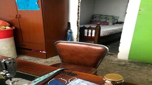 Une pièce comprenant une machine à coudre, une chaise, un lit et une petite table.