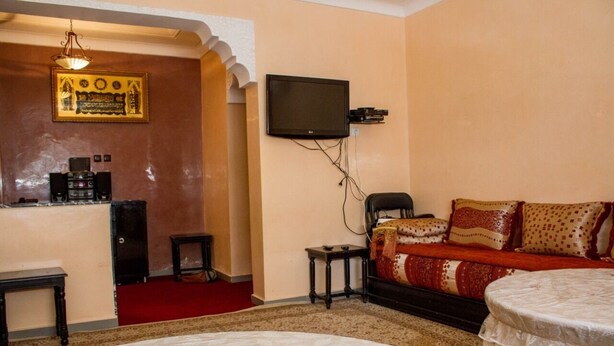 Una camera d'albergo con un letto, una TV a muro, un tavolino e un divano.