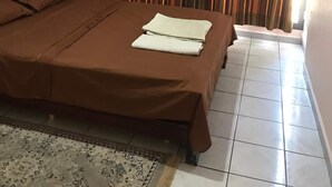 Una camera da letto con un letto, tende, un comodino e una lampada da terra.