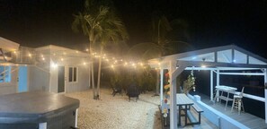 A covered outdoor area with a barbecue grill, seating, and string lights.