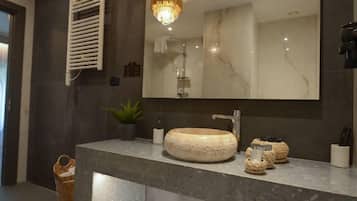 Un baño con un espejo grande, un lavabo redondo y una planta en maceta.
