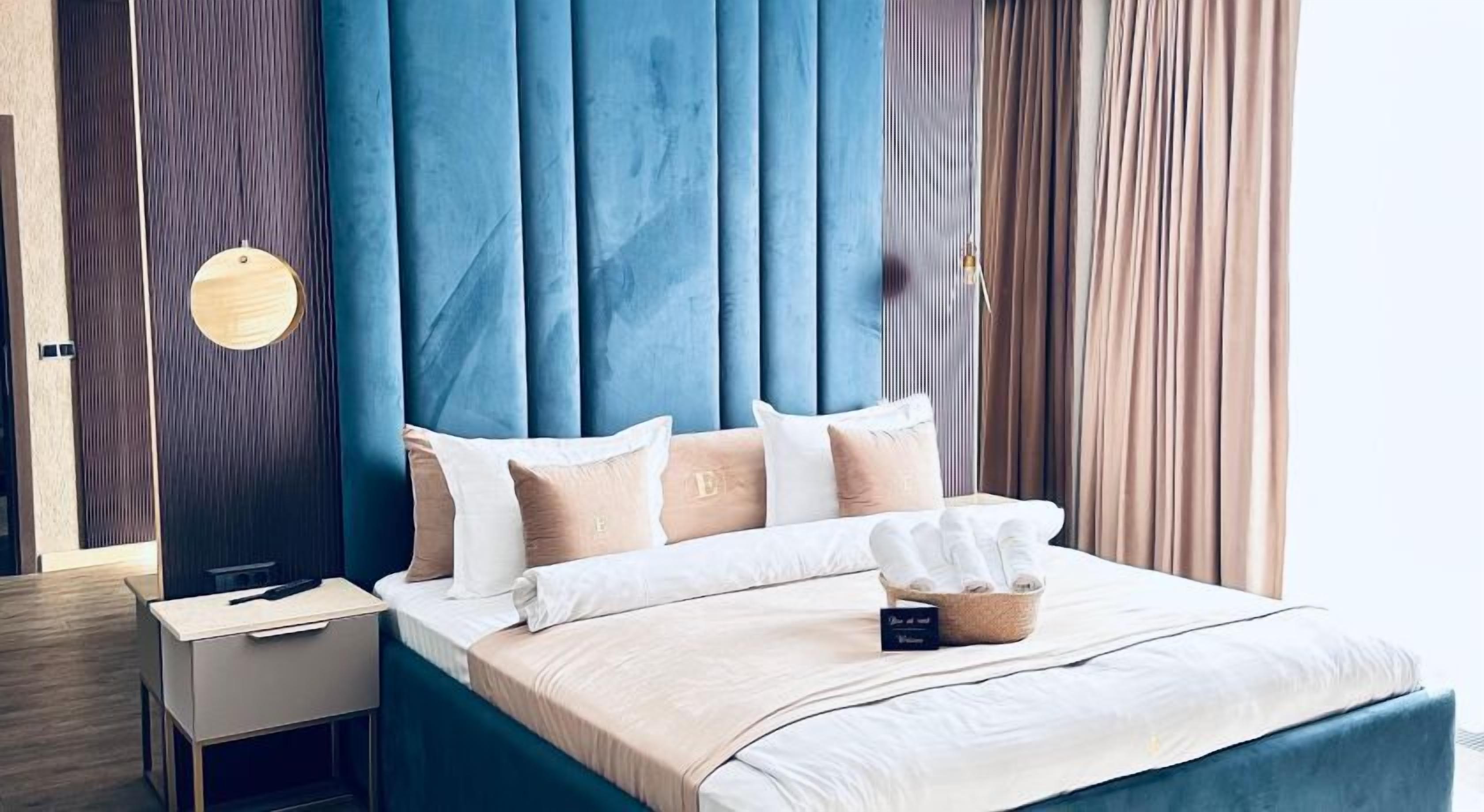 Une chambre moderne avec une tête de lit bleue, une table de chevet et un lit avec une literie blanche et une boîte à mouchoirs.