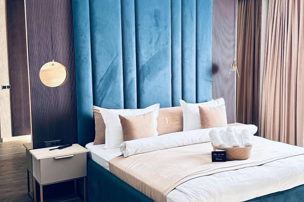 A modern bedroom with a blue headboard, a bedside table, and a bed with white bedding and a tissue box.