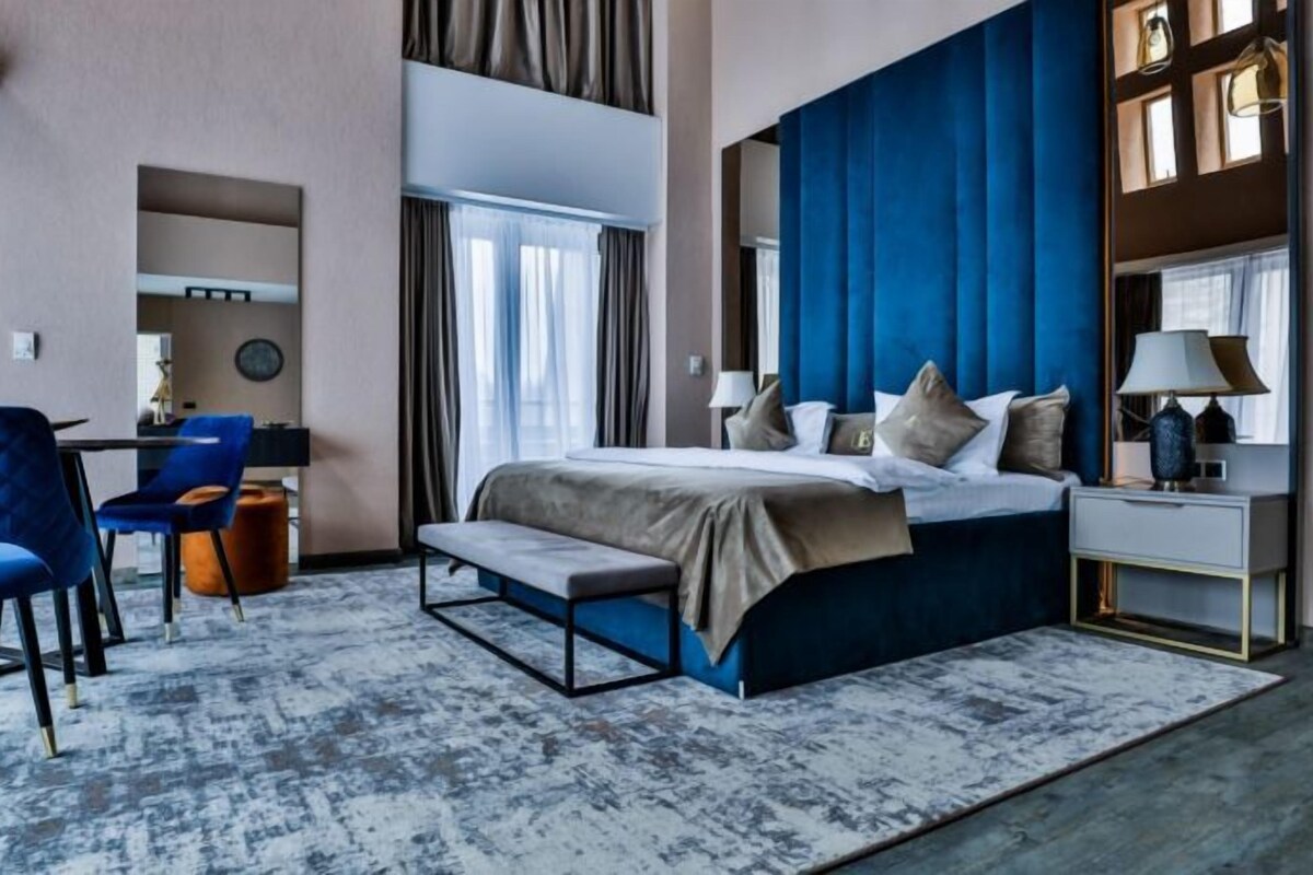 A modern hotel room with a large bed, a desk, and a chair.