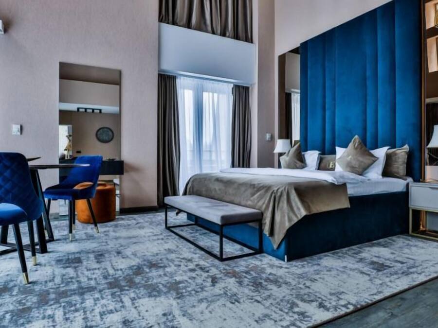 A modern hotel room with a large bed, a desk, and a chair.