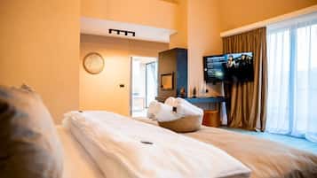 Habitación de hotel con dos camas, un televisor y un amplio ventanal con cortinas.
