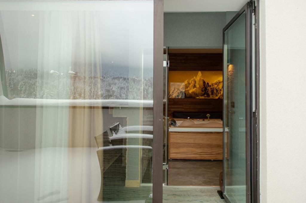 A modern bathroom with a glass shower enclosure, a wooden vanity, and a view of a snowy landscape.
