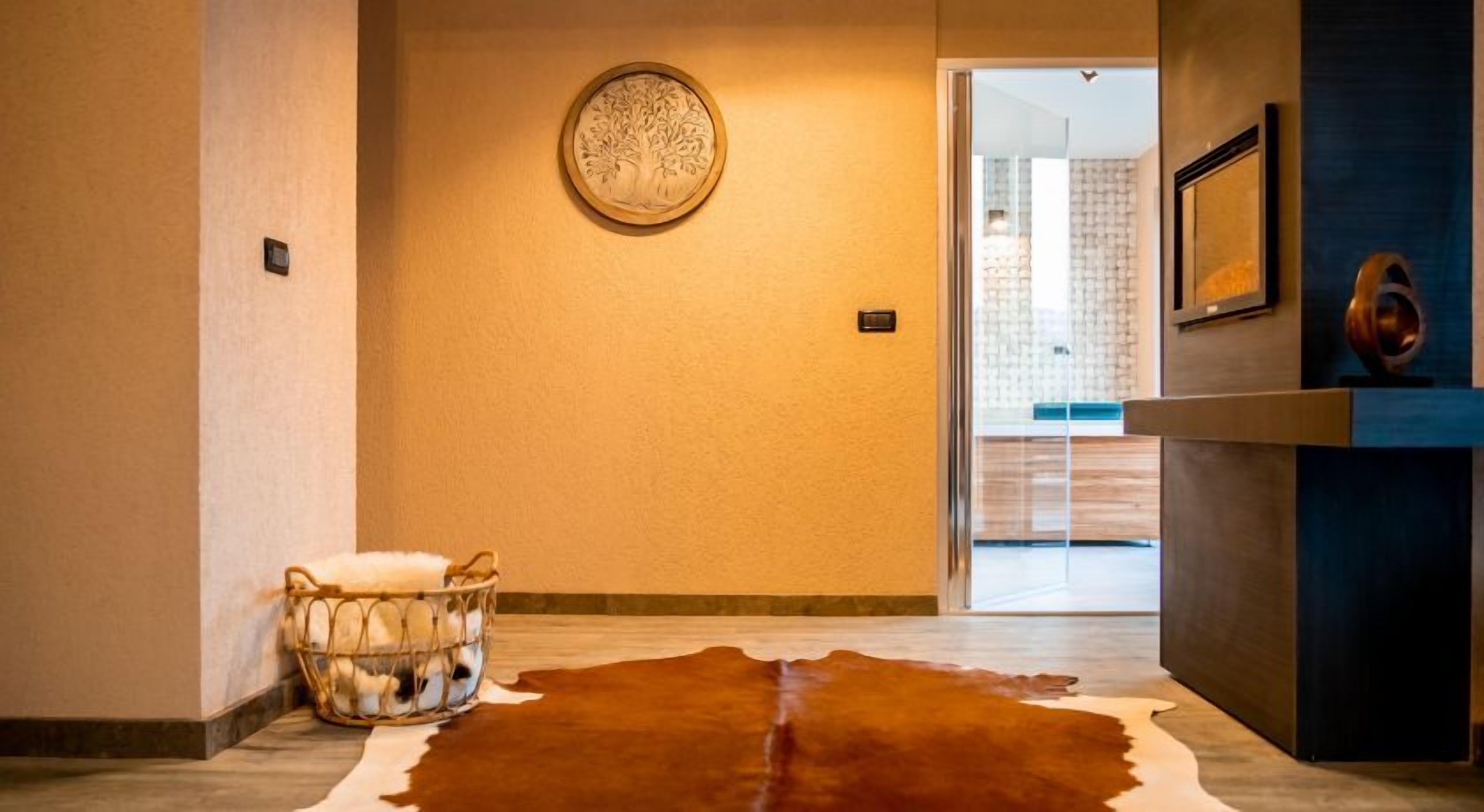 A hallway with a cowhide rug, a basket with white items, and a wall-mounted circular object.
