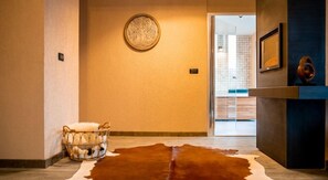 A hallway with a cowhide rug, a basket with white items, and a wall-mounted circular object. - Elexus Poiana Brasov (Brasov)