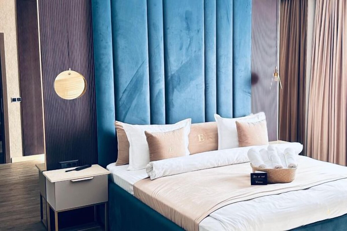 A modern bedroom with a blue headboard, a bedside table, and a bed with white bedding and a tissue box.