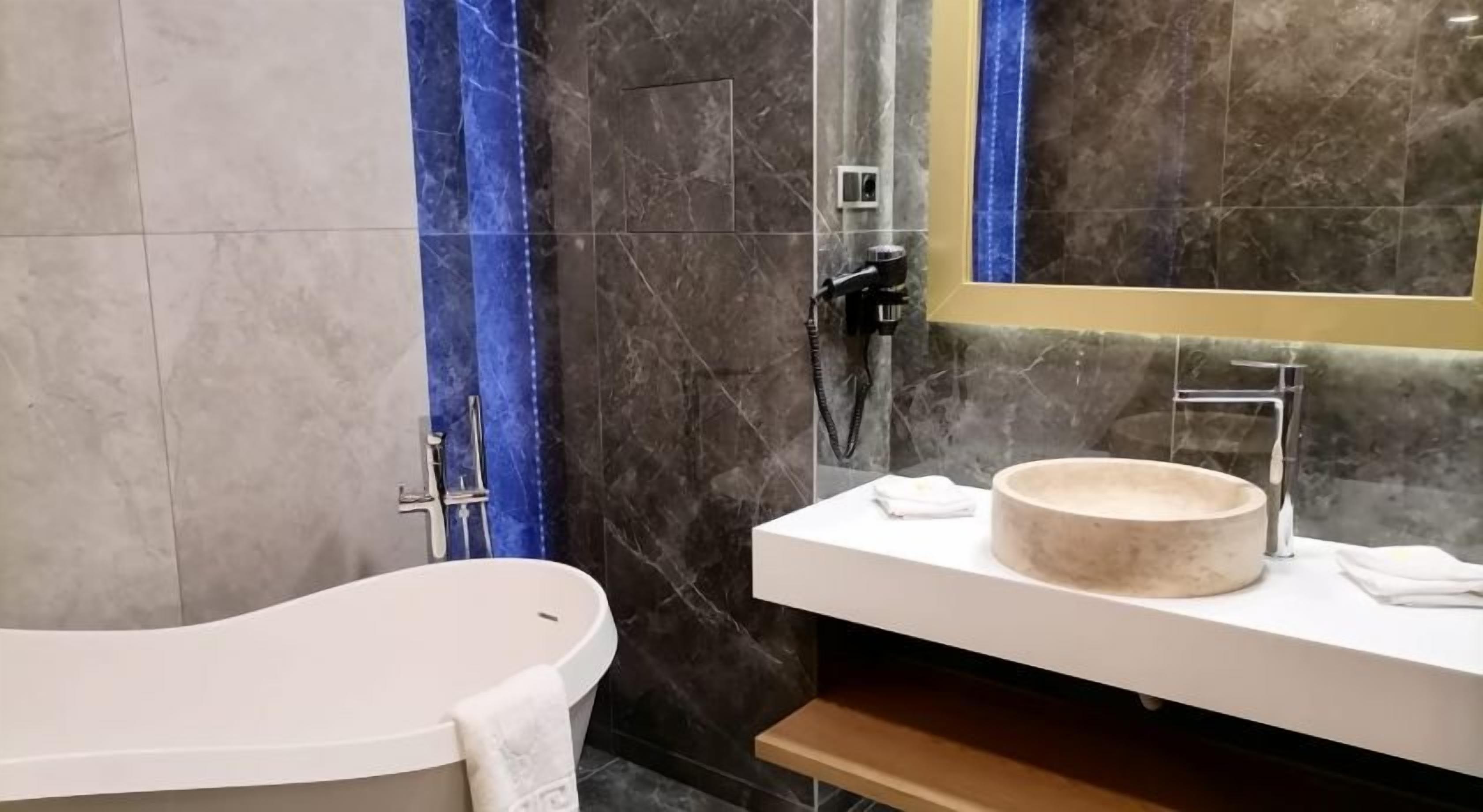 Un baño moderno con una bañera independiente, un lavabo redondo y un espejo.