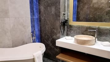 Un baño moderno con una bañera independiente, un lavabo redondo y un espejo.