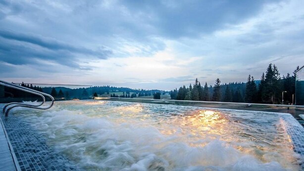 A hot spring with a view of a forested landscape in the background. - Elexus Poiana Brasov (Brasov)