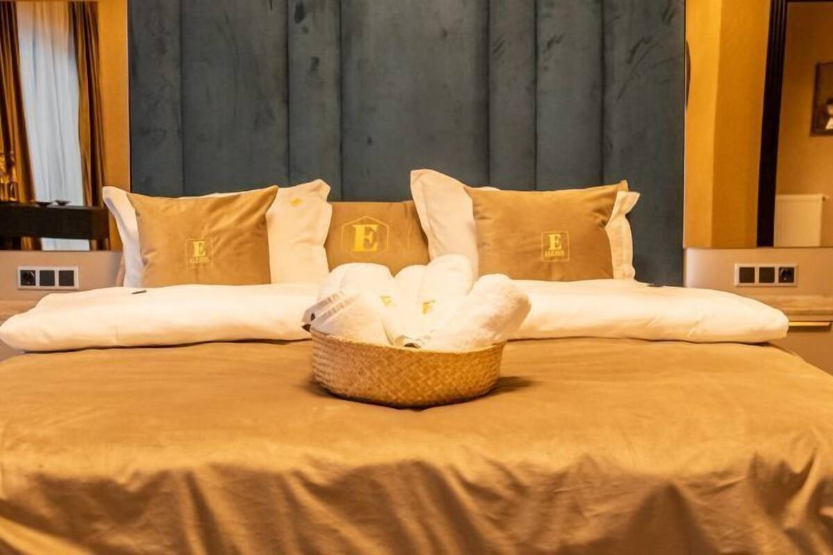 A neatly made bed with a large, fluffy white towel in the center, two matching pillows, and a headboard with a logo.
