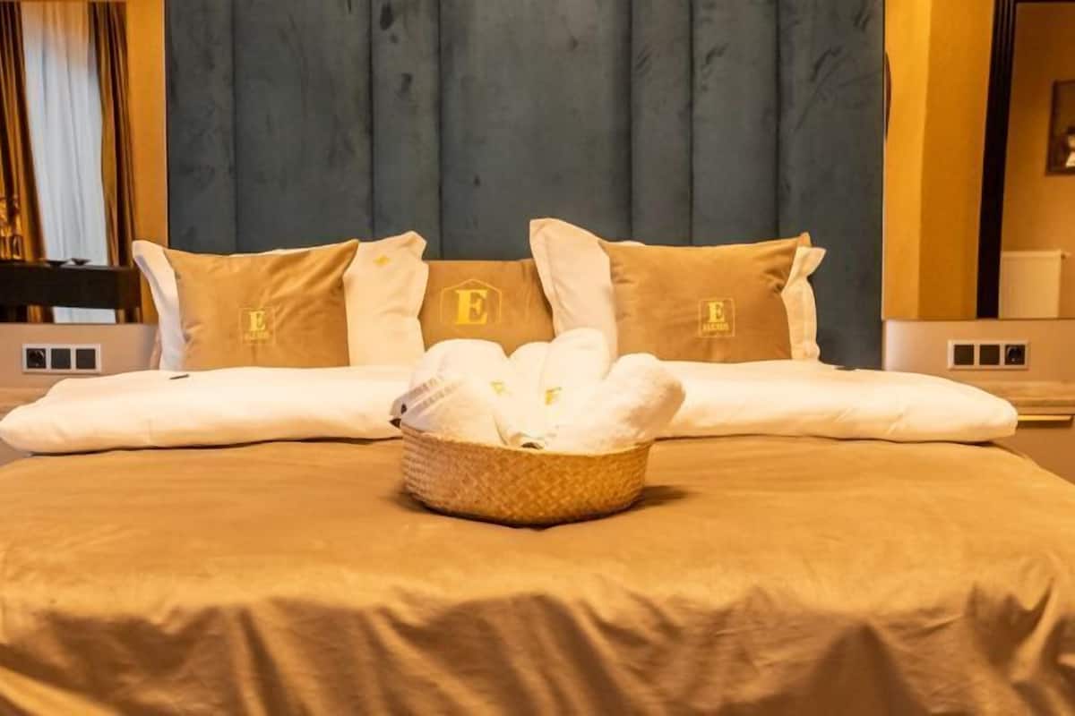 Un lit bien fait, avec une grande serviette blanche et moelleuse au centre, deux oreillers assortis et une tête de lit ornée d’un logo.