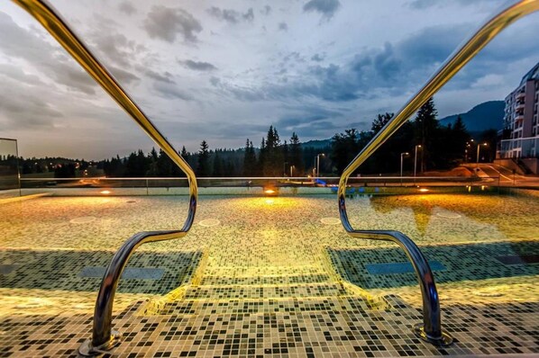 Una piscina con suelo de baldosas y barandillas metálicas.