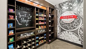 A snack and treat display area with various packaged snacks and a chalkboard sign welcoming visitors to the Sweet Shop. - Hampton Inn Longview (Longview)
