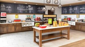 A modern kitchen with wooden cabinets, a central island, and various kitchen appliances. - Hampton Inn Longview (Longview)