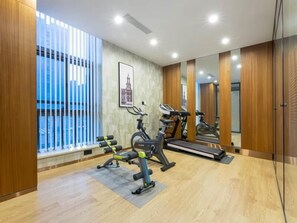 Et moderne fitnessrum med træningsudstyr, store vinduer og en spejlvæg.