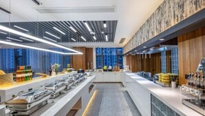 A modern kitchen with a long counter, stainless steel appliances, and wooden accents. - Greentree Eastern Suzhou Dushu Lake Guoyuan Road Subway Station Hotel (Suzhou)