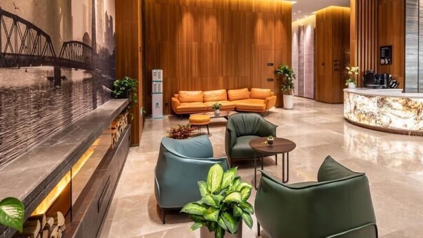A modern lobby with a reception desk, a sofa, and two armchairs. - Greentree Eastern Suzhou Dushu Lake Guoyuan Road Subway Station Hotel (Suzhou)