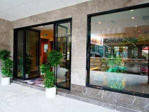 A modern building entrance with glass doors and potted plants. - Greentree Eastern Chongqing Jiefangbei Children's Hospital Hotel (Chongqing)