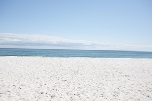En sandstrand med klart himmel og roligt hav.