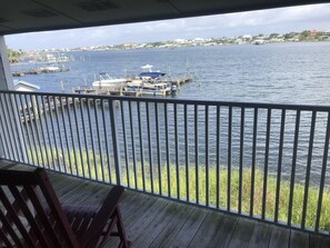 A view from a covered balcony overlooking a marina with boats docked and a distant shoreline with buildings. - A 22 Sundown Condominiums (Pensacola)