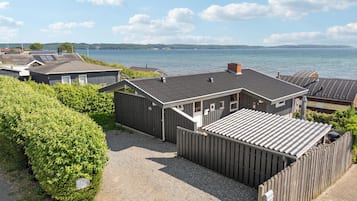 Rivi mökkejä, joiden edessä on sorapäällysteinen ajotie ja puinen aita, ja josta avautuu näkymä järvelle.