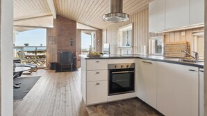 Una cocina moderna con una isla central, horno empotrado y vista al océano.