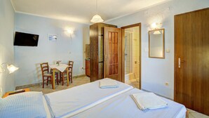 A hotel room with a bed, a desk with a chair, a television, and a shower area. - Gorgeous apartment in Senj with house sea view (Senj)