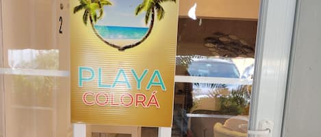 Señal con palmeras y una playa, indicando la ubicación 'Playa Colorá'.
