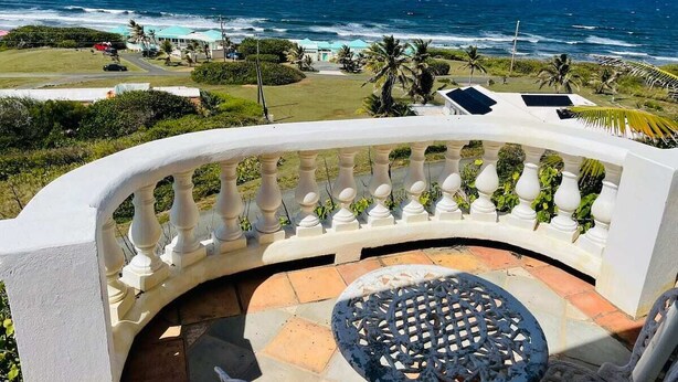 A curved balcony with a white balustrade, a round table, and chairs. - Caribbean Island Retreat, 200 degree water views, trade winds and soothing waves (Christiansted)