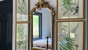 A room with a large mirror, a wooden dresser, and four framed botanical illustrations on the wall. - Happy mtn. home, enjoy 7 acres & 2 ponds, 1/2 mile to DuPont State Forest gate! (Cedar Mountain)