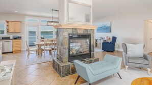 Una sala de estar moderna con chimenea de piedra, comedor y vistas al exterior.