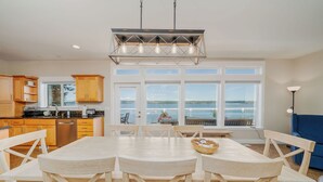Una cocina amplia con armarios de madera, una mesa de comedor con sillas y un ventanal con vistas al agua.