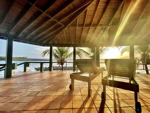 A covered outdoor seating area with a view of the sea and palm trees. - SeaCasa, the spectacular water-front home overlooking the reef (West End)