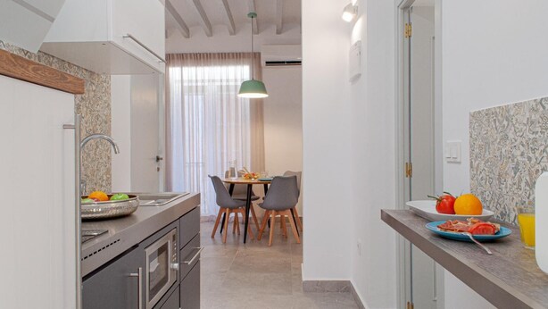 A modern kitchen with a dining area, featuring a sink, stove, and a dining table with chairs.